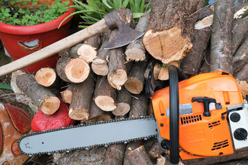 Professional gasoline powered chainsaw on piles of cut wood.