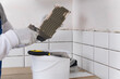 the master of laying tiles, takes a mixture for gluing finishing materials to the wall, close-up