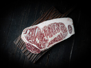 Piece of Wagyu beef steak. Raw beef steak on a wooden background in a butcher shop. Japanese premium product.