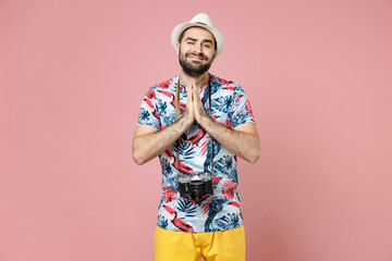 Wall Mural - Pleading traveler tourist man in hat photo camera hold hands folded in prayer gesture begging about something isolated on pink background. Passenger traveling on weekends. Air flight journey concept.