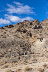 Desert garbage and truck tracks below an old mining head frame in the nevada desert