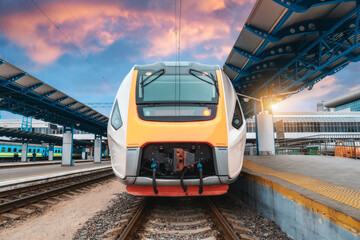 Wall Mural - high speed train on the railway station at sunset. industrial landscape with moving modern intercity