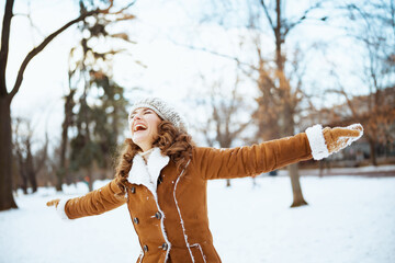 smiling stylish woman rejoicing outside in city park in winter