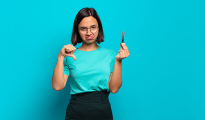 Wall Mural - young hispanic woman feeling cross, angry, annoyed, disappointed or displeased, showing thumbs down with a serious look