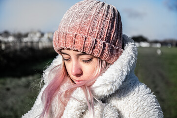 Young girl or woman with a pink hat and a white coat in winter. 