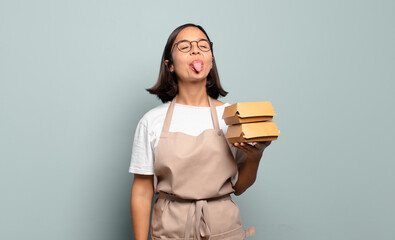 Wall Mural - young hispanic woman with cheerful, carefree, rebellious attitude, joking and sticking tongue out, having fun