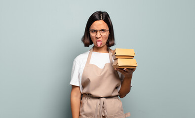 Wall Mural - young hispanic woman feeling disgusted and irritated, sticking tongue out, disliking something nasty and yucky