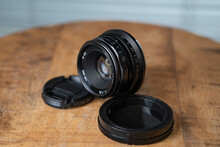 Closeup Shot Of Camera Lens With Cover On A Wooden Tabl