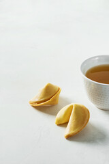 Wall Mural - Tea in white Asian cup with fortune cookies on light background with copyspace.