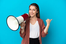 Young Caucasian Woman Isolated On Blue Background Shouting Through A Megaphone And Pointing Side
