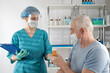 © TSViPhoto - Female nurse holding a clipboard folder, giving prescription drug orange pill jar  to adult senior man. Doctor's appointment hospital healthcare case