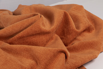 Closeup of a wrinkled natural orange chenille fabric texture