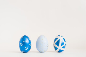 Three Easter golden decorated eggs on white background. Minimal easter concept. Happy Easter card with copy space for text. Top view, flatlay.