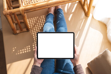 Top view mockup image of a woman holding and using tablet pc with blank desktop white screen at home