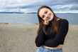 © Mat Hayward - Teenage girl outside at Alki Beach in West Seattle with a view of the Puget Sound and the city of Seattle in Washington State.