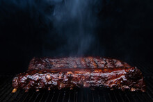 Hot Babyback Ribs Cooking On A Pellet Smoker Grill With Caramelized Barbecue Sauce Slathered On Top. 