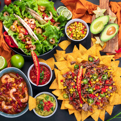 Hispanic mexican food, nachos, guacamole, meat tacos on dark background