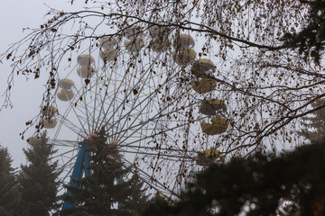 Ferris wheel in an old abandoned park in the autumn in thick fog