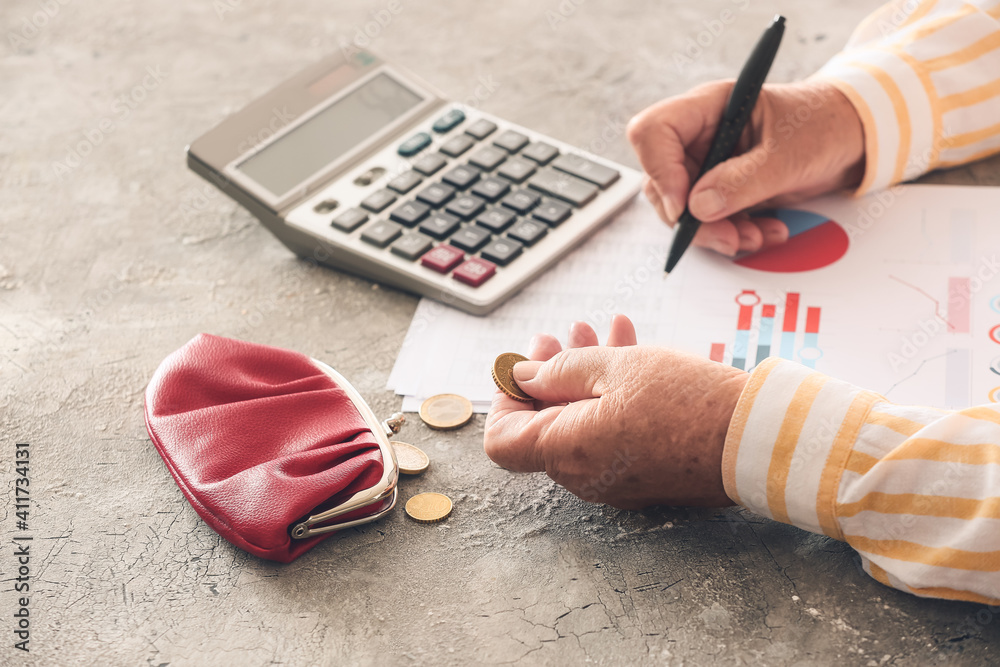 Senior woman calculating expenses at table. Concept of pension