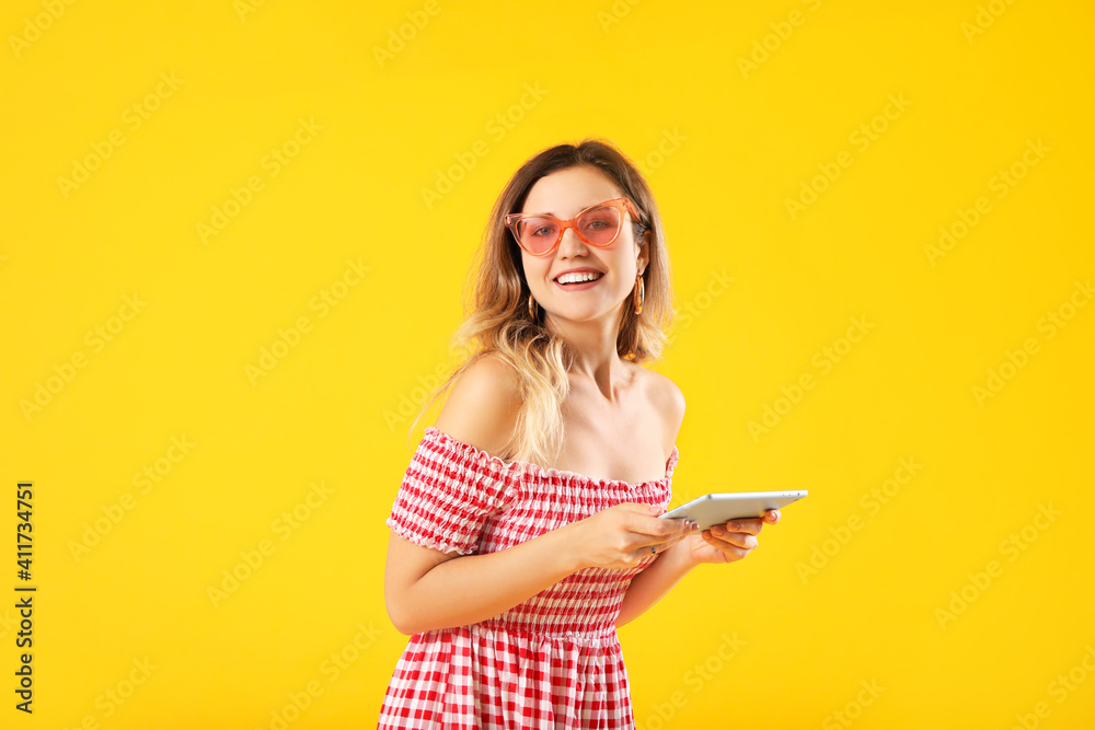 Young woman with tablet computer on color background
