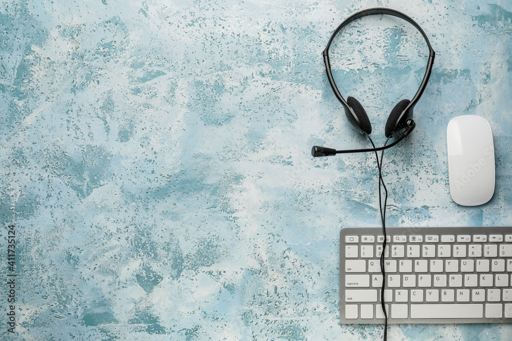 Headset with computer keyboard and mouse on color background