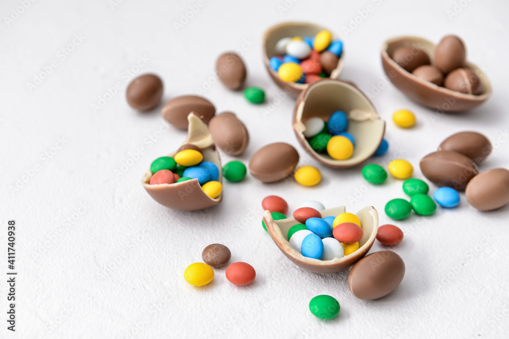 Tasty chocolate eggs and candies on white background