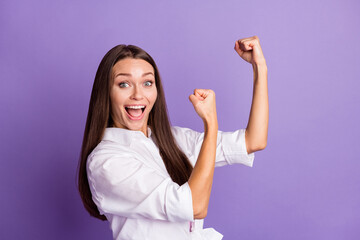 Wall Mural - Photo portrait of excited girl with raised fists ready to fight isolated on vivid purple colored background