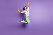© deagreez - Full length photo of girl jump raise fists enjoy wear pants sneakers white shirt isolated purple color background