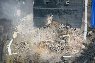 Yellow excavator destroys building. Heavy duty machine is demolishing a brick building. Demolition of the building . Demolition construction work aerial drone photo