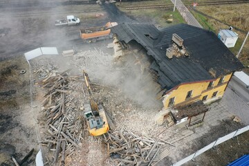 Yellow excavator destroys building. Heavy duty machine is demolishing a brick building. Demolition of the building . Demolition construction work aerial drone photo