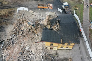 Yellow excavator destroys building. Heavy duty machine is demolishing a brick building. Demolition of the building . Demolition construction work aerial drone photo