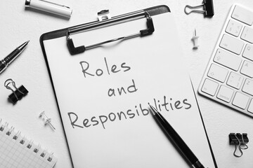 clipboard with sheet of paper saying roles and responsibilities among office supplies on white table