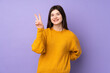 © luismolinero - Young Ukrainian teenager girl over isolated purple background smiling and showing victory sign