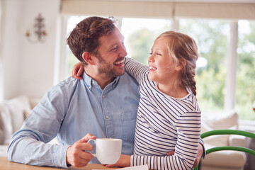 Loving Daughter At Home With Father Sitting At Table With Paperwork