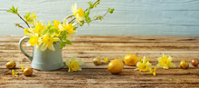 Golden Easter Eggs And Yellow Flowers On Wooden Background
