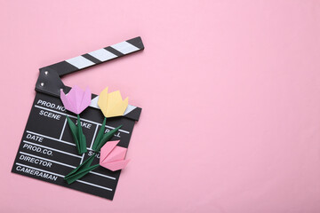 Wall Mural - Clapperboard and origami tulips on pink background. Filmmaking concept. Top view