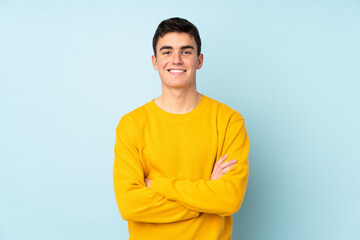 teenager caucasian handsome man isolated on purple background keeping the arms crossed in frontal po