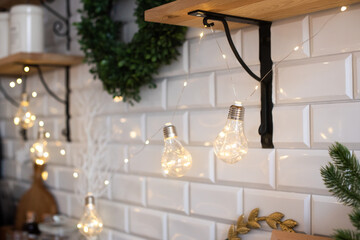 Wall Mural - the kitchen is decorated with a garland of incandescent lamps. brick wall and shelves in light colors. cute and cozy. holiday, christmas