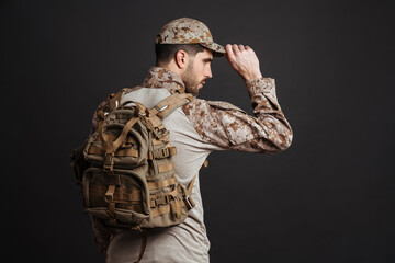 Wall Mural - Confident masculine military man in uniform posing with backpack