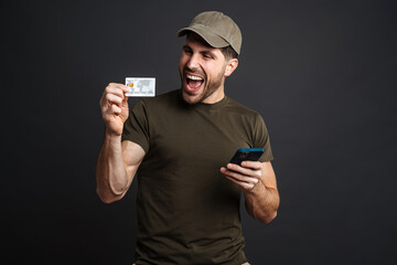 Wall Mural - Excited military man posing with cellphone and credit card