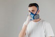 A man in a respirator mask with an increased degree of protection against harmful environmental factor, chemicals or covid19. Full face mask. Isolated on a grey background.