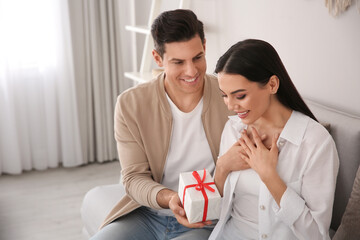 Wall Mural - Man presenting gift to his beloved woman at home. Valentine's day celebration