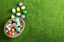 Wicker Basket With Easter Eggs On Green Grass, Flat Lay. Space For Text