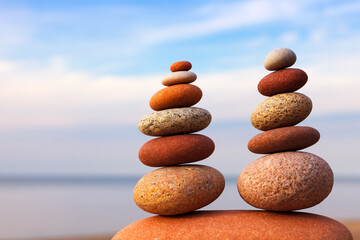 Two Rock zen pyramids of colorful pebbles on a beach on the background of the sea.