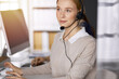 © rogerphoto - Businesswoman talking by headset while sitting in sunny office. Call center and diverse people group in business