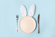 pink empty Easter plate with Bunny ears on blue background