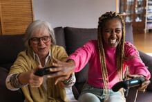Black Woman Joking With An Older Woman As They Play A Game Console