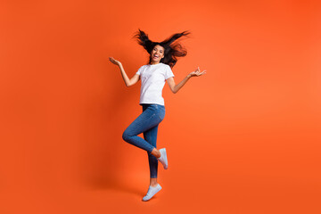 Sticker - Full length photo of cheerful girl throw hair have fun wear white t-shirt jeans footwear isolated orange color background