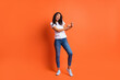 © deagreez - Full length photo of girl dance have fun wear white t-shirt jeans footwear isolated orange color background