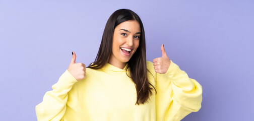 Wall Mural - Young caucasian woman over isolated background giving a thumbs up gesture